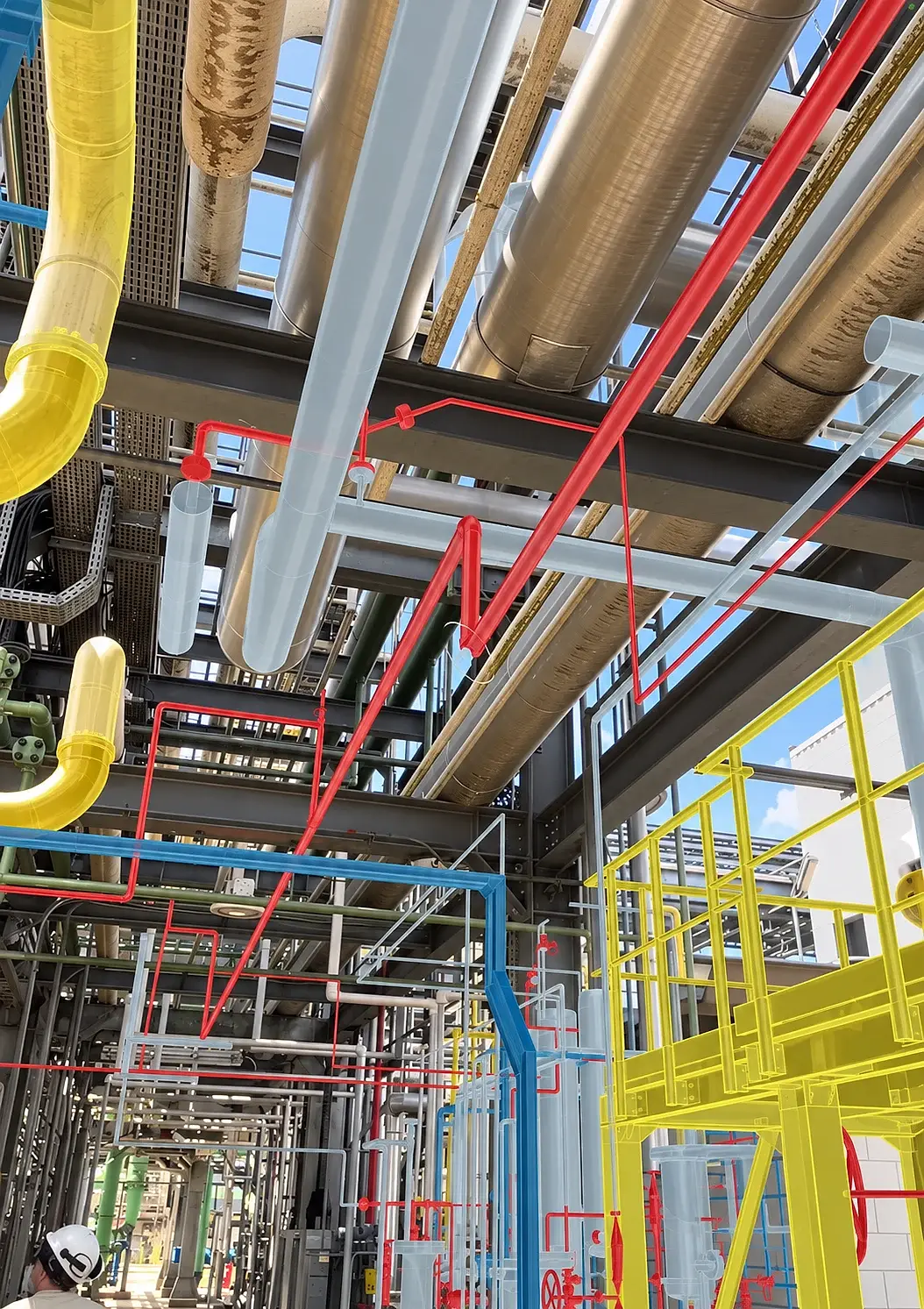 Tubulações e estruturas do modelo 3D, em vermelho, azul e amarelo, sobrepostas em Realidade Aumentada às tubulações já instaladas de uma planta industrial